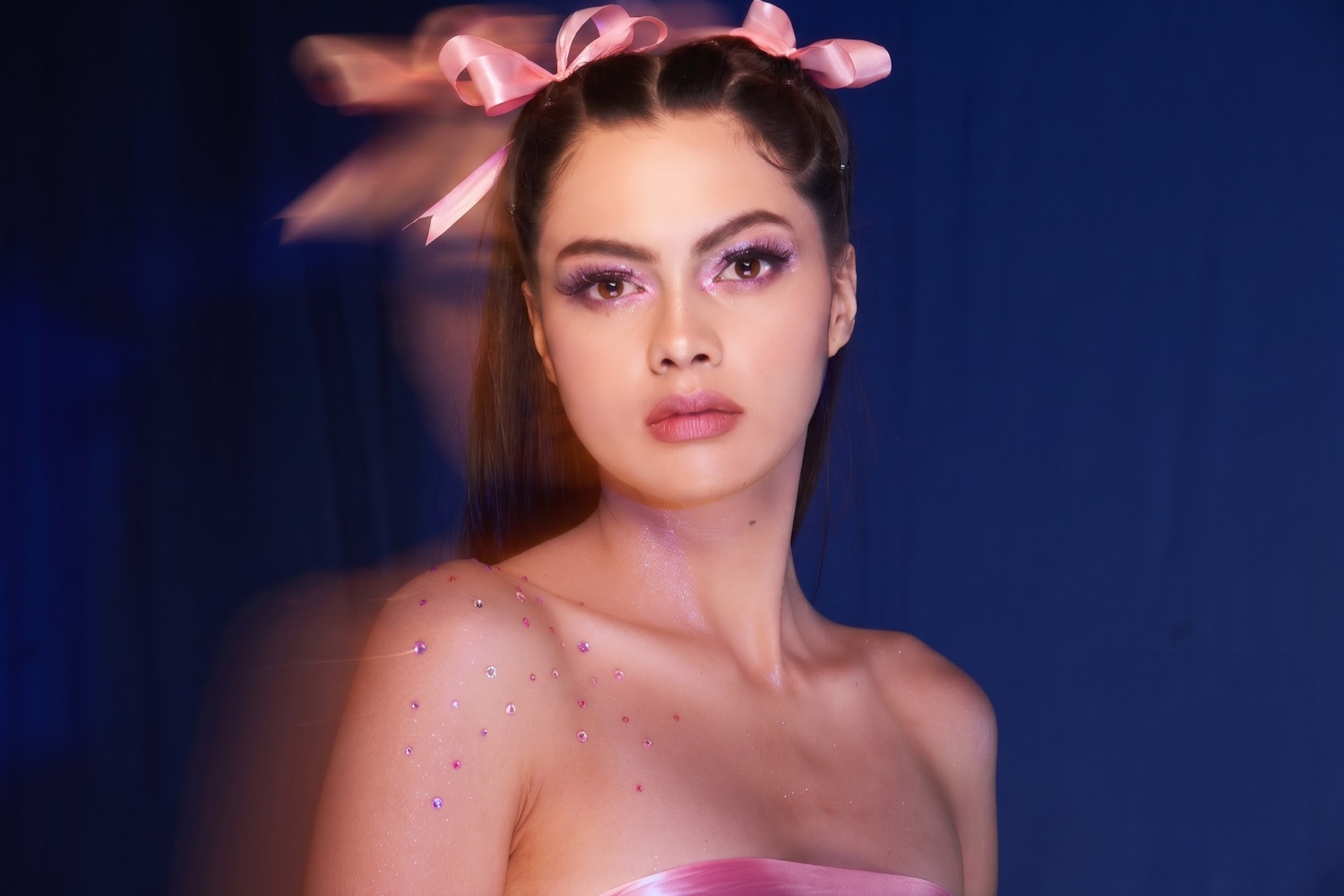 Editorial beauty look with pink shimmer eye makeup and satin hair ribbons