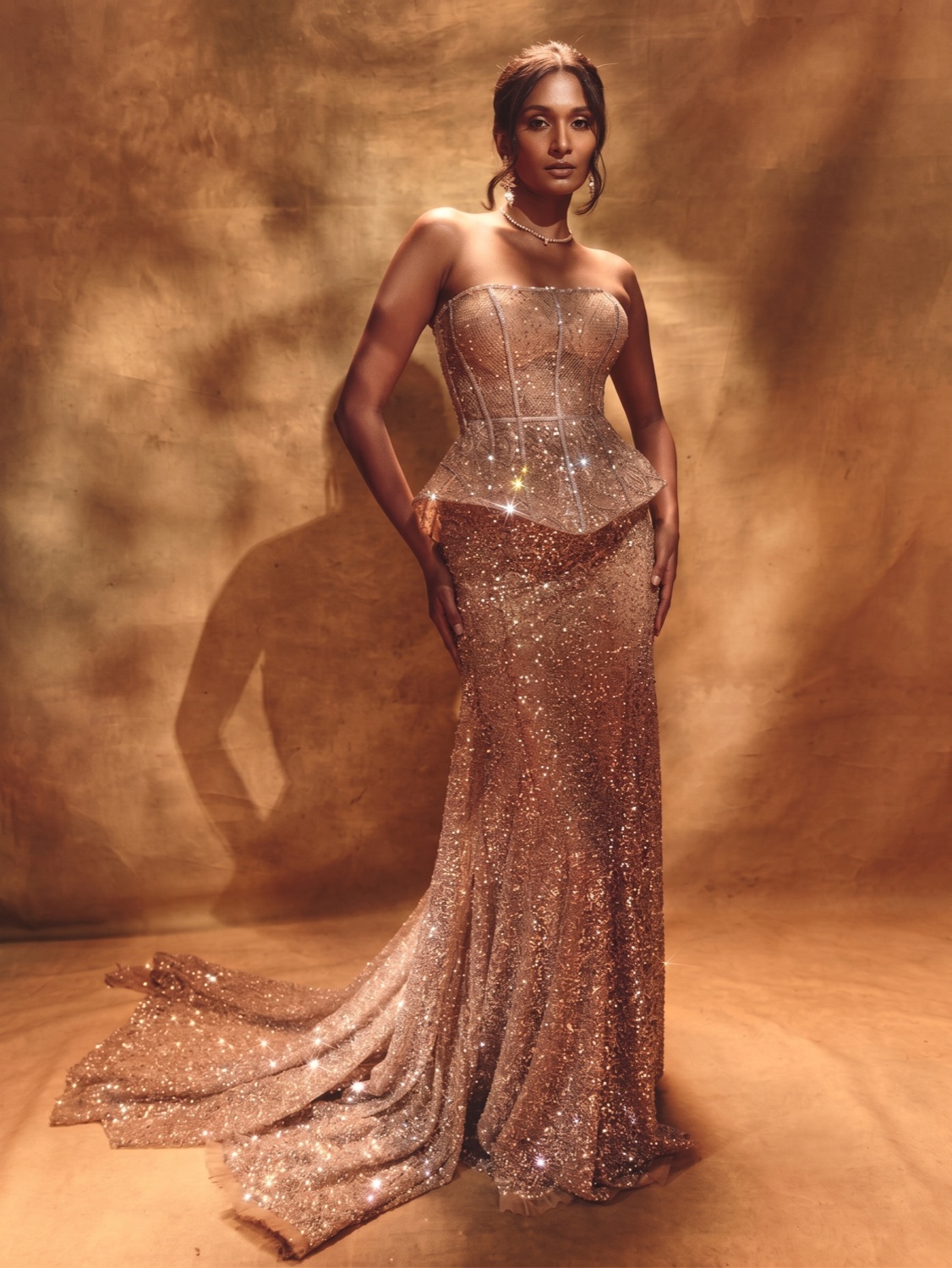 Full-length portrait in a shimmering champagne gown against a warm backdrop